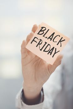 Woman holding sticky note Black Friday text