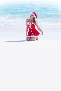 Beautiful woman in Mrs. Claus custume on tropical beach, Christmas vacations concept