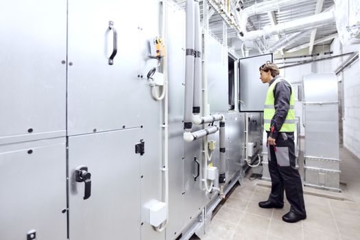 Worker in electrical switchgear room of CNC plant