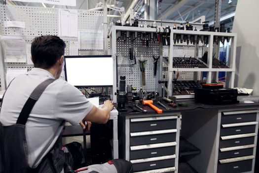 Worker at workplace with computer and tools at CNC factory