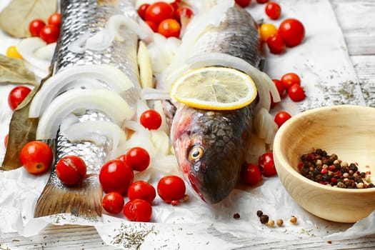 Two carcasses of raw marine fish in seasonings and tomatoes
