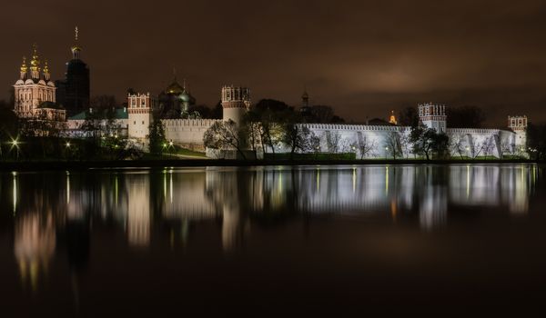 Night view illuminated Novodevichy Convent of Our Lady of Smolensk is reflected in the water of the nearest pond. Moscow, Russia