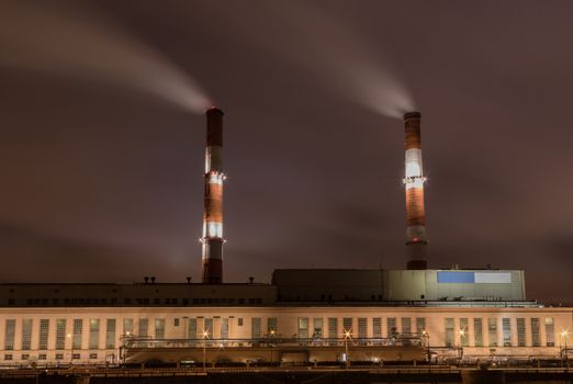 Factory with two smoke stack against sky at night
