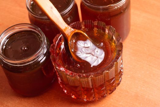 Honey in vintage jars, wooden spoon dipped in honey, wooden background,