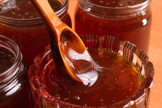 Honey in vintage jars, wooden spoon dipped in honey, wooden background,