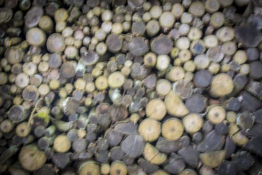 Abstract background with a stack of firewood logs prepared for winter, with blurry settings, great composition for your design