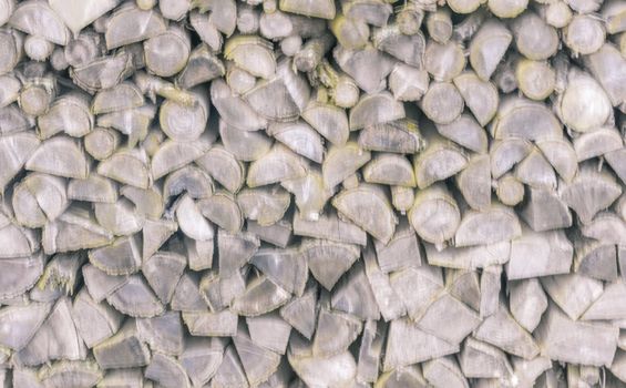 Blurry background with a pile of chopped firewood logs in different shapes