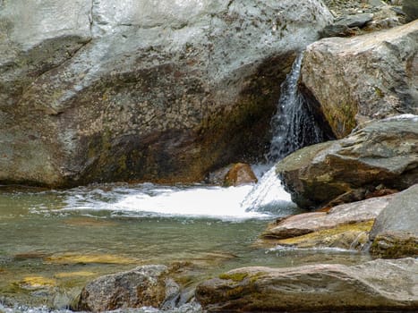 a beautiful small waterfall flows into the forest pond