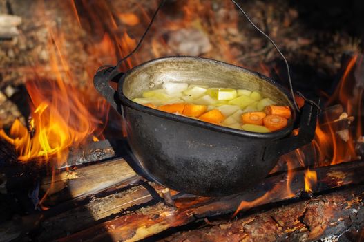 vegetable soup in old tourist pot at fire place Summer trekking activity