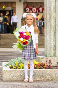 Grower Baby girl first-grader with a bouquet of flowers at the school