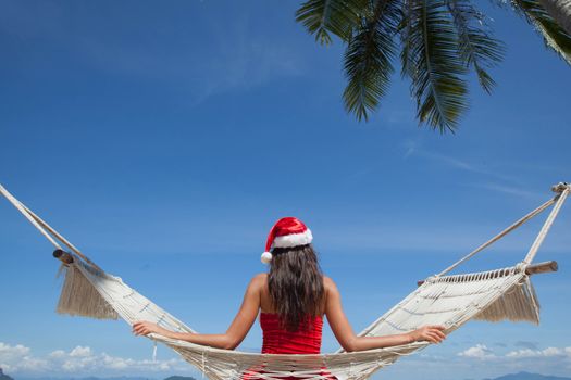 Woman in hammock on tropical beach celebrating Christmas