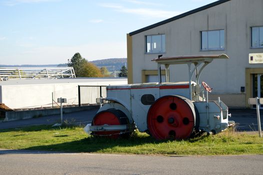 Old roller with tarmac with vibrator in front of a stone building.