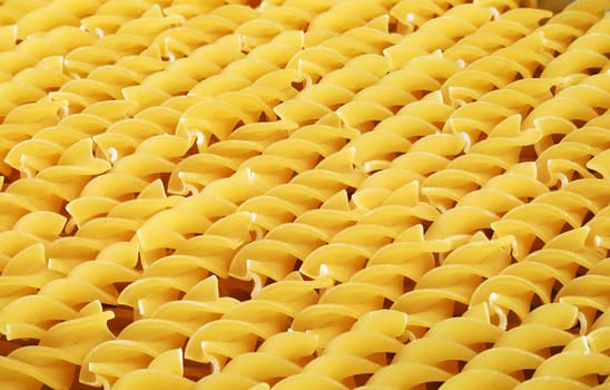 Italian yellow short uncooked fusilli pasta closeup sorted diagonally for background or texture.
