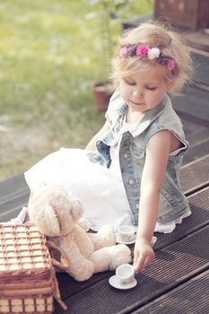 Pretty girl playing with teddy bear outdoors