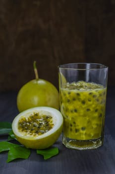 Fresh passion fruit juice in glass with passion fruits over wooden background , still life