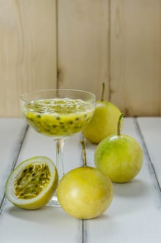 Fresh passion fruit juice in glass with passion fruits over wooden background , still life