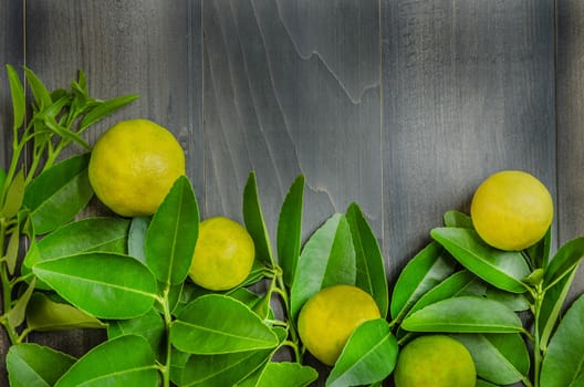 top view of wooden background with fresh lime and green leaves