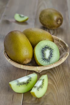 kiwi fruit and sliced with bamboo basket on wooden background