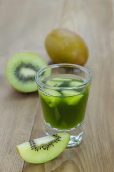 glass of kiwi juice with fresh fruits on wooden table