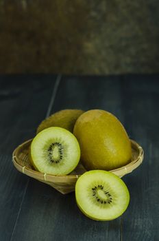 kiwi fruit and sliced with bamboo basket on wooden background , still life