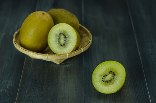 kiwi fruit and sliced with bamboo basket on wooden background , still life