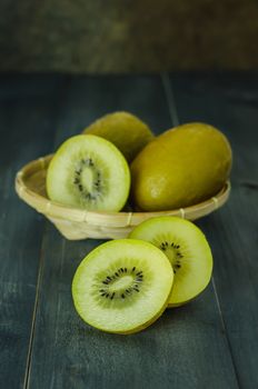 kiwi fruit and sliced with bamboo basket on wooden background , still life