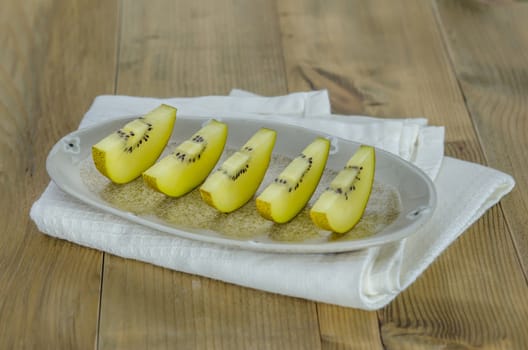 sliced of golden kiwi fruit  on dish over wooden background