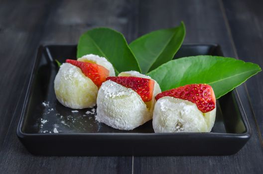 Strawberry Daifuku Mochi Japanese dessert on black dish over wooden background