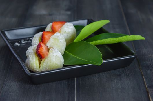 Strawberry Daifuku Mochi Japanese dessert on black dish over wooden background
