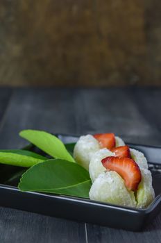 Strawberry Daifuku Mochi Japanese dessert on black dish over wooden background