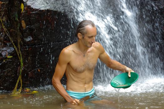 a man gold panning in a river with a sluice box