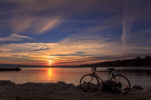 A picture of the sunset at the coast with bicycle