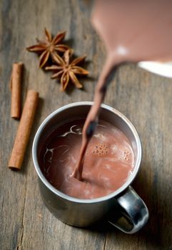 Hot chocolate with cinnamon stick on wooden table