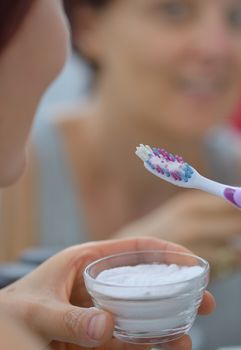 Woman brightening teeth with sodium bicarbonate 