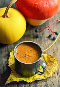 Cup of coffee on autumn leaf on the wooden background