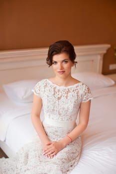 The girl in a wedding dress sitting on the sofa waiting for the groom