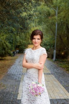 Bride in the park in the alley on a rainy day