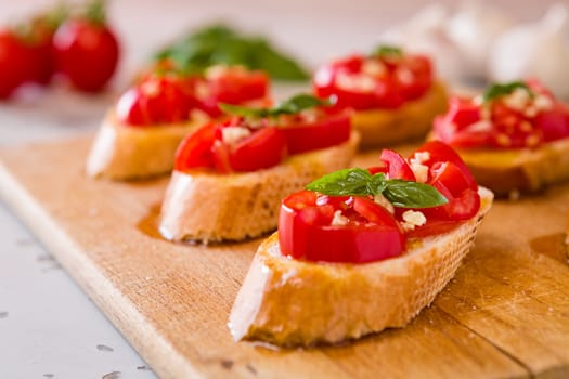 Closeup of Italian bruschetta with tomato, basil and garlic on a chopping board