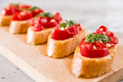 Closeup of Italian bruschetta with tomato, basil and garlic on a cutting board