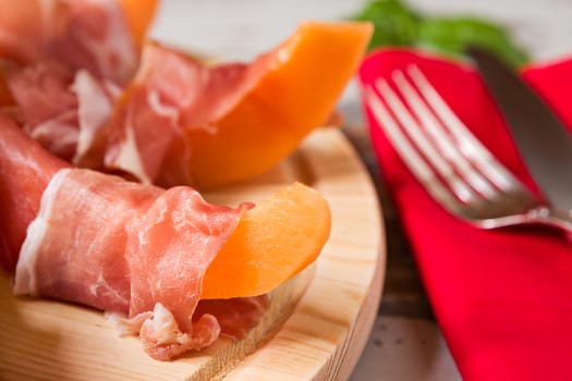 Close up of prosciutto and melon Italian appetizer on a cutting board
