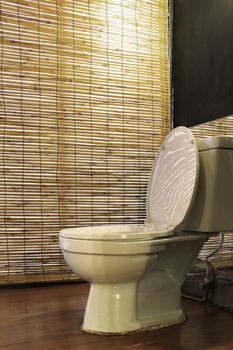 White toilet bowl with bamboo weave curtain background