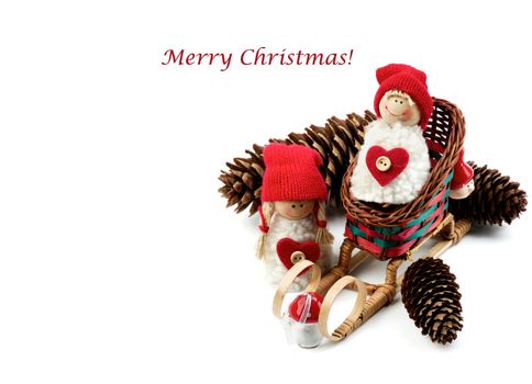 Christmas Decoration Concept with Handmade Dolls in Knit Hats, Fir Cones, Sleigh and Inscription closeup on White background