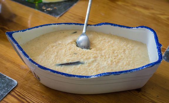 Creamy rice pudding with vanilla bean in ceramic vessel in the form of a boat on the table