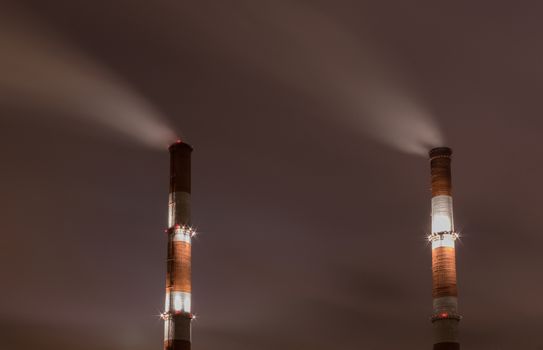 Two smoke stack against sky at night
