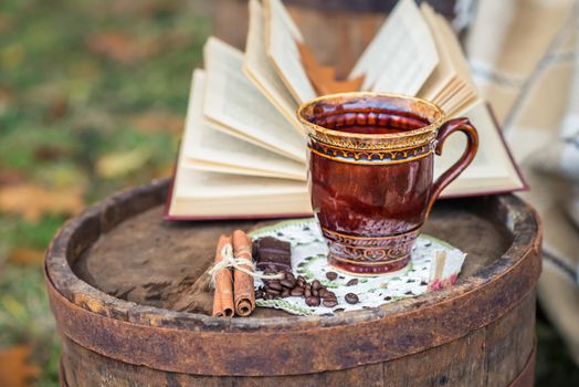 still life with cinnamon sticks, coffee beans and coffee cup on the old oak barrel in the garden autumn