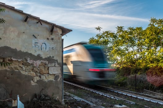 Train running near an abandoned rural rail station