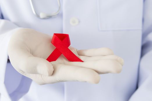 doctors hands holding red ribbon. World AIDS Day concepts.