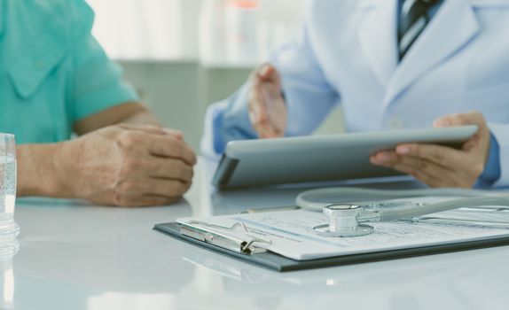 close up stethoscope on application form with doctor and patients in background.