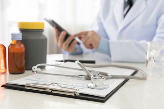 stethoscope and document on desk's doctor by doctor working in background