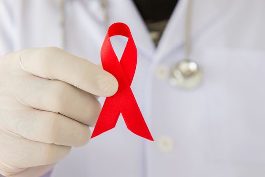 doctors hands holding red ribbon. World AIDS Day concepts.